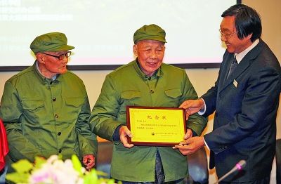 侵华日军南京大屠杀遇难同胞纪念馆馆长朱成山（右）向参加过南京保卫战的老战士程云（左）、李高山（中）颁发&ldquo;纪念状&rdquo;。新华社发